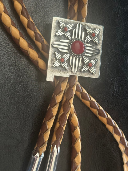 Authentic Southwestern artisan jewelry: sterling silver Zia bolo tie with Mediterranean coral tips and elk skin cord