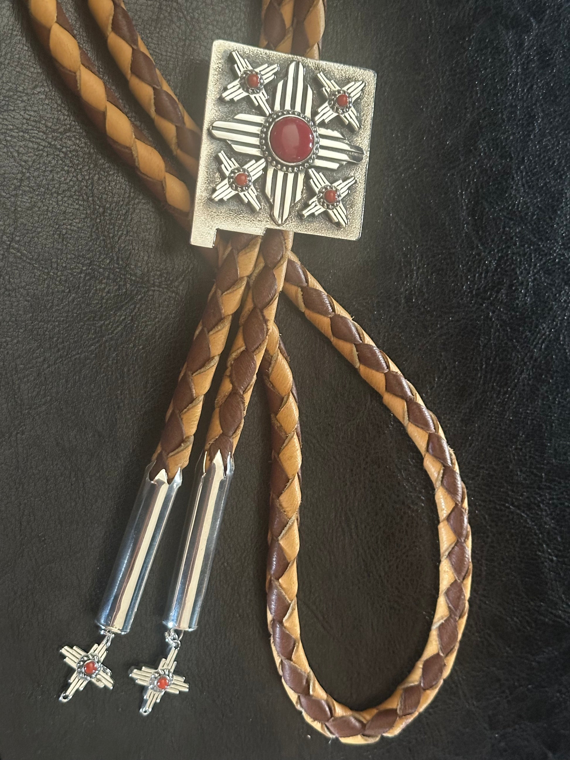 Luxury Western bolo tie handmade by Shane Casias featuring sterling silver Zia pendant and vibrant red coral details